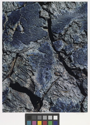 A color close-up photograph of a rough blue-tinged rock with cracks.