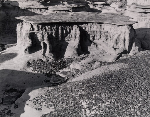 A black-and-white photograph of a mesa surround by scrubby vegetation as viewed from above.