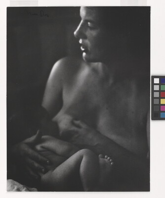 A black-and-white photograph of a topless White woman breastfeeding a baby.