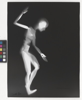 A black-and-white photograph of a white person-shaped puppet dancing on a black background.
