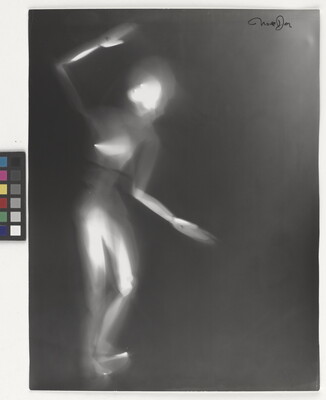 A black-and-white photograph of a white person-shaped puppet dancing on a black background.