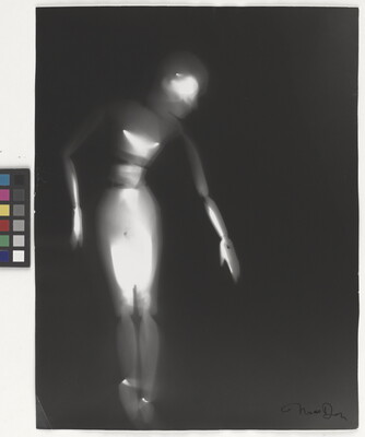 A black-and-white photograph of a white person-shaped puppet dancing on a black background.