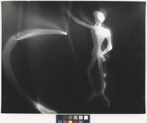 An abstract black-and-white photograph of an illuminated white figure and blurred lights against a black background.