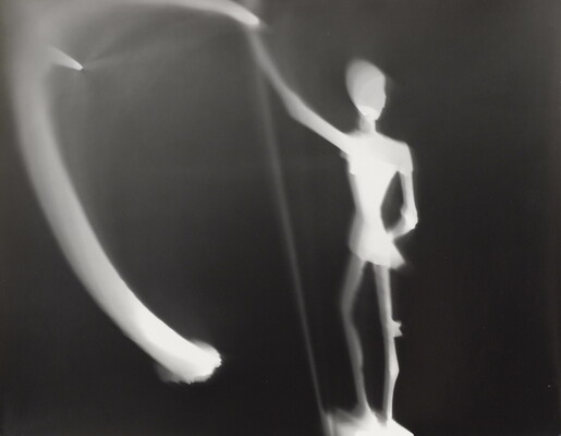 An abstract black-and-white photograph of an illuminated white figure and blurred lights against a black background.