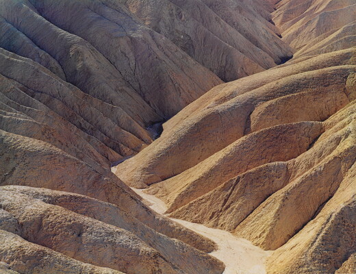 A color photograph of a desert valley between two arid mountains.