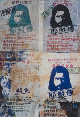 A color photograph of heavily distressed flyers with images of Jesus surrounded by Asian text pasted to a wall.