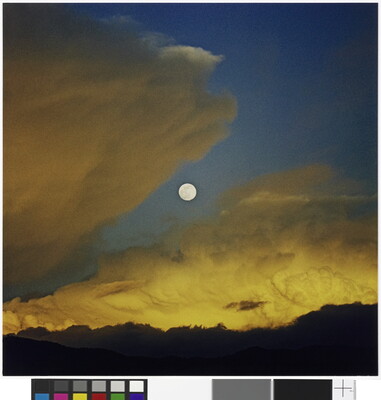 A color photograph of a full moon in a dark blue sky with yellow swirling clouds.