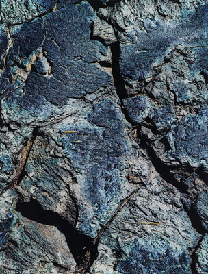 A color close-up photograph of a rough blue-tinged rock with cracks.