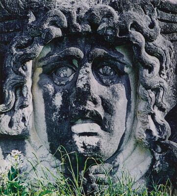 A color photograph of an ancient stone carving of a woman's face with snakes for hair.