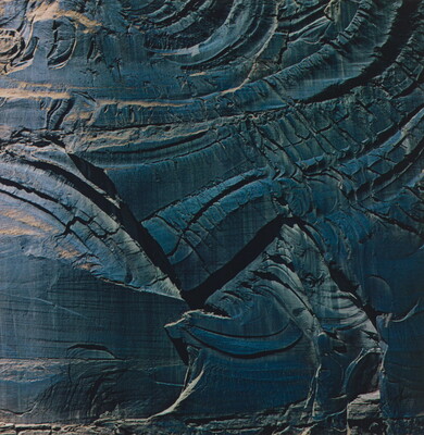 A color photograph of shiny dark stone with cracks swirling through it.