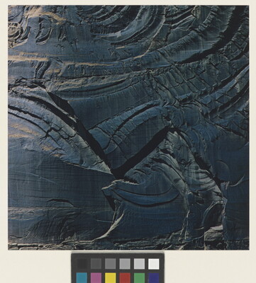 A color photograph of shiny dark stone with cracks swirling through it.