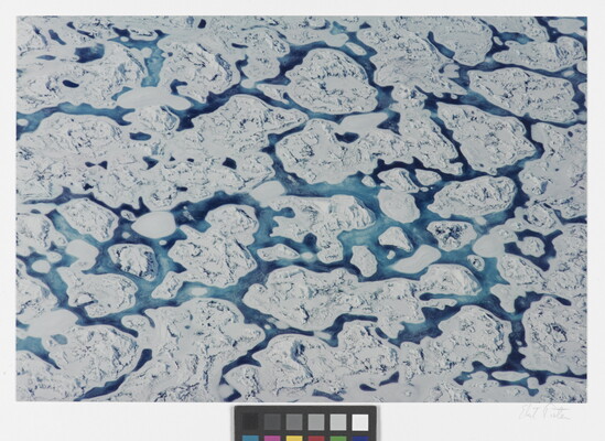 A color aerial photograph of white ice floes with ribbons of blue water running through them.