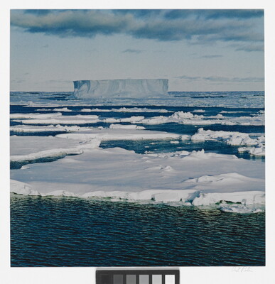 A color photograph of an ocean covered with ice floes and a large, flat-topped iceberg in the distance.