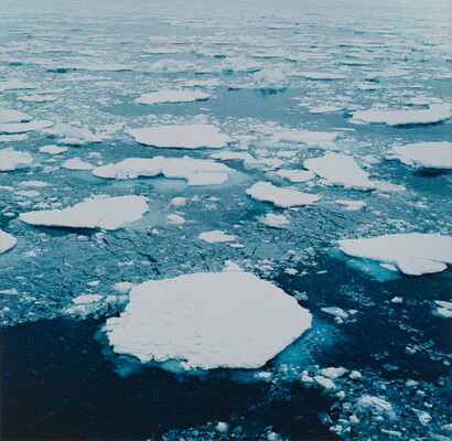 A color photograph of white ice floes in dark ocean water.