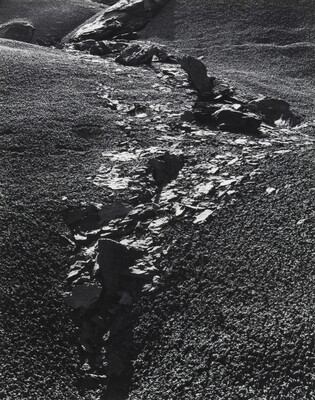 A black-and-white photograph of rocks and rock flakes bisecting a gravelly slope.