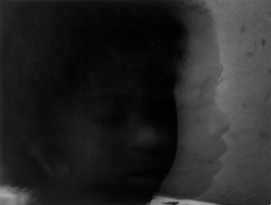 A black-and-white photograph of the faces of two young Black children that looks like it might be double exposed.