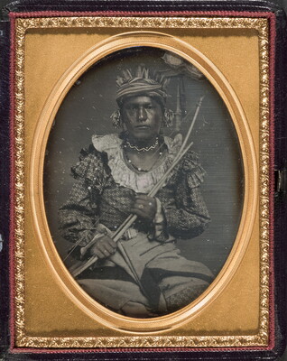 A framed black-and-white photograph of an Indigenous person holding a bow and arrow across their chest.