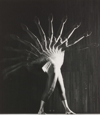 A black-and-white photograph of a male dancer in motion; an arc of multiple arms from front to back indicate motion.