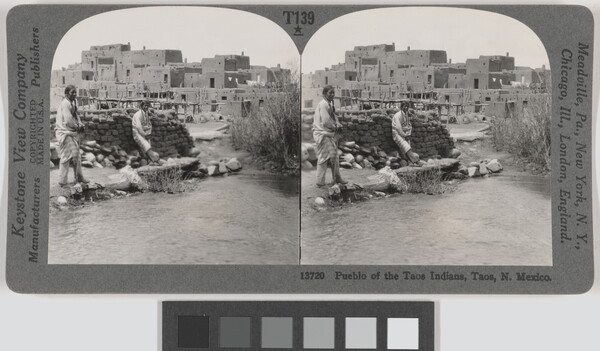 Two almost identical black-and-white photographs side by side of two Native Americans standing in front of a pile of mud bricks with an adobe pueblo in the background.