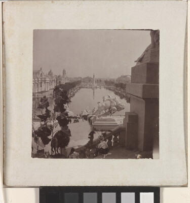 A black-and-white photograph of a tree-lined reflecting pool taken from the steps of a building showing other buildings and several sculptures, including a bison, lining the pool.