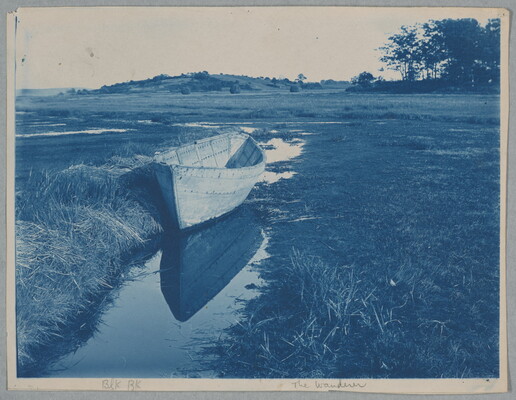 A blue-tinted photograph of an empty rowboat in a shallow creek surrounded by fields.