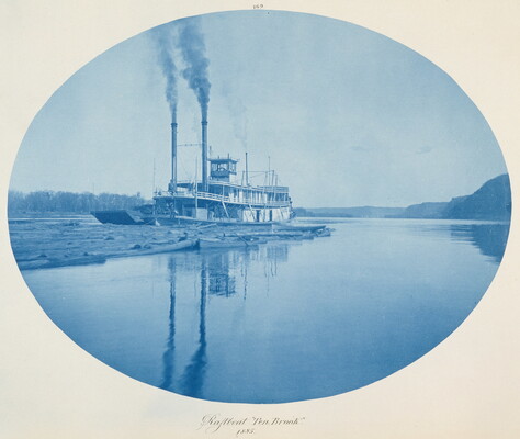 A blue oval-shaped photograph of a large boat, smokestacks billowing smoke, on a still river.