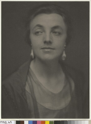 A sepia-toned portrait photograph of a White woman, hair tied back to show her dangling earrings.