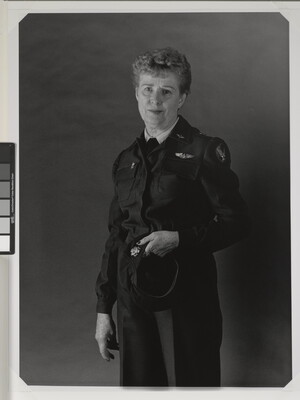 A black-and-white portrait photograph of an older White woman with short gray hair wearing an Air Force uniform, holding her hat in one hand.