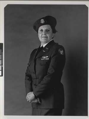 A black-and-white portrait photograph of a middle-aged White woman wearing an Air Force uniform, including a beret, hands crossed at her hips.