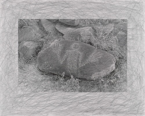 A black-and-white photograph of an oval-shaped stone with a human figure, hands held up, drawn in white on its surface.