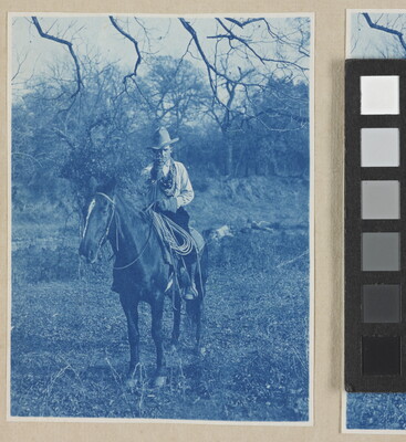 A black-and-white photograph of a man wearing a cowboy hat on horseback, pointing his revolver toward the viewer.