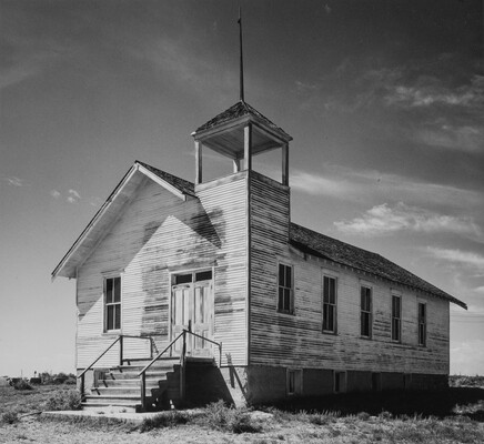A black-and-white photograph of a white, clapboard church with peeling paint viewed at an angle.