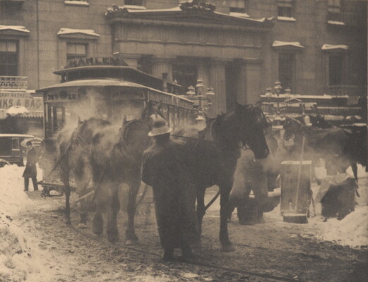 A black-and-white photograph of horses pulling a trolley on a busy street covered with slush and snow.