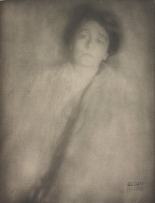 A soft-focus black-and-white portrait photograph of a White woman with short hair wearing a shawl or stole around her shoulders.