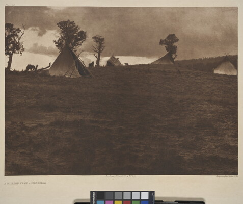 A sepia-toned photograph of a hilltop campsite with tipis amongst the scattered trees.