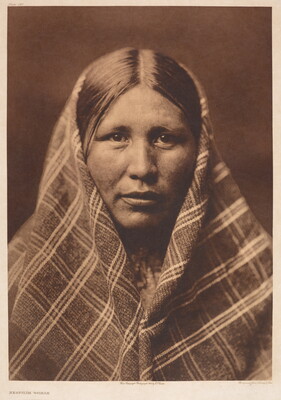 A sepia-toned portrait photograph of an American Indian woman, a plaid shawl over most of her head and shoulders.