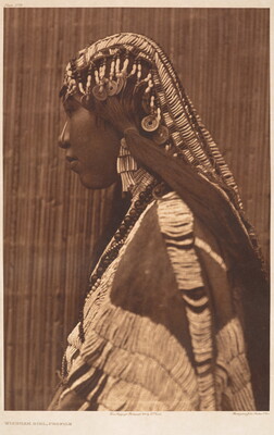 A sepia-toned portrait photograph of an Indigenous woman in profile wearing a beaded hair covering over her braids, beaded necklaces, and an elaborately beaded tunic.