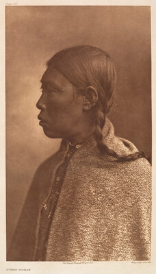 A sepia-toned portrait photograph of an Indigenous woman in profile, wearing her dark hair in braids and a shawl over her shoulders fastened at her neck.