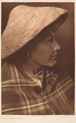 A sepia-toned portrait photograph of an Indigenous woman in profile, wearing a conical hat and a plaid blanket around her shoulders.