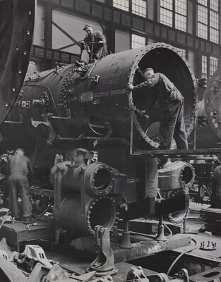 A black-and-white photograph of a few men building a locomotive car.