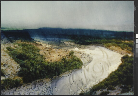 A slightly blurry color photograph of a river valley in vibrant blues, greens, and whites.