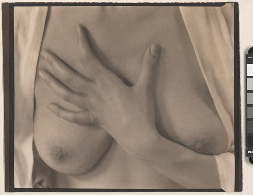 A sepia-toned photograph of the torso of a White woman with her hand on her bare chest between her breasts.