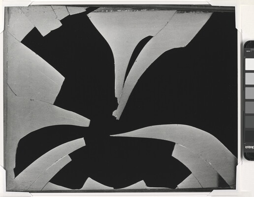 A black-and-white photograph of a pane of broken glass with many pieces missing in front of a black background.