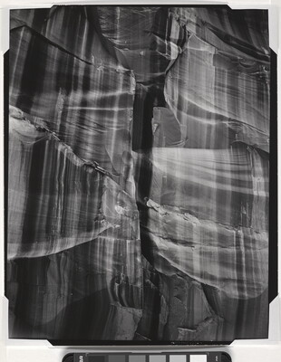 A black-and-white abstract photograph of a close up of a rocky canyon wall with vertical stripes.