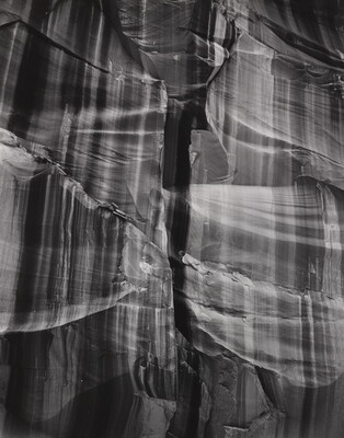 A black-and-white abstract photograph of a close up of a rocky canyon wall with vertical stripes.