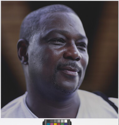A color photograph of the head and shoulders of a smiling Black man with a goatee and short hair.