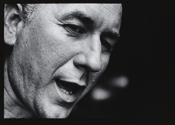 A black-and-white close-up photograph of the face of a White man who appears to be speaking.