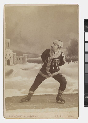 A sepia-toned studio portrait photograph of a White man dressed in winter clothes pretending to ice skate.
