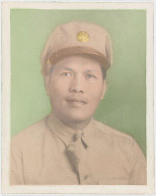 A faded color photograph of a man with Asian features wearing a khaki military hat and uniform against a green background.