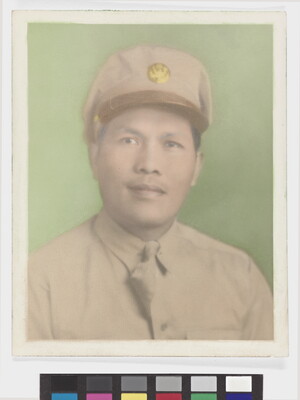 A faded color photograph of a man with Asian features wearing a khaki military hat and uniform against a green background.